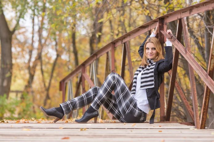 Woman in plaid outfit on bridge.